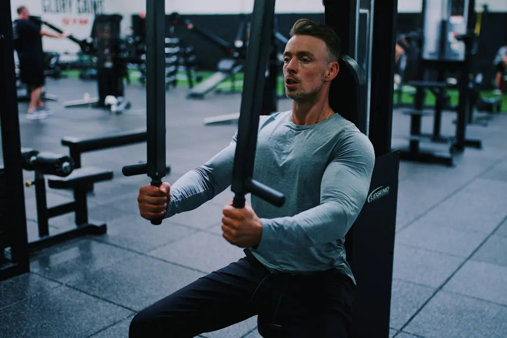 Man kneeling on gym floor with kettlebell, woman standing beside him